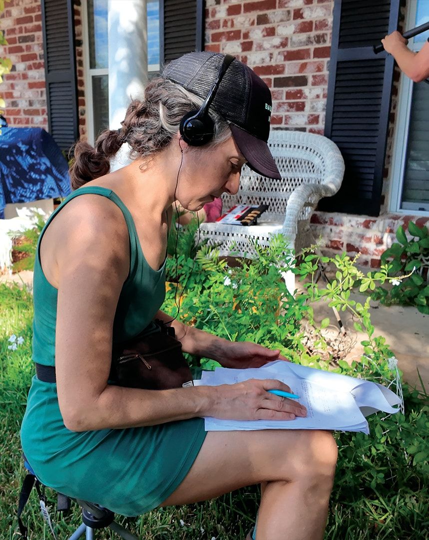 A crew member in headphones reading notes in the front yard